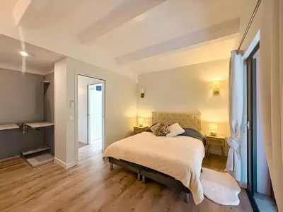 a bedroom with a bed and two lamps and a door at Villa A Muredda, 6 pers, jacuzzi, 15 min plage en voiture in Porto-Vecchio