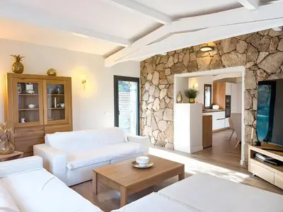 a living room with a white couch and a stone wall at Villa A Muredda, 6 pers, jacuzzi, 15 min plage en voiture in Porto-Vecchio