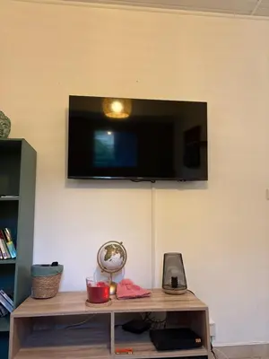 a tv hanging on a wall with a wooden table at A casa Patricia in Sari Solenzara