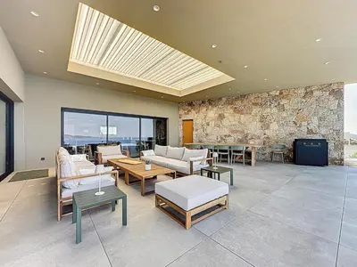 a living room with couches and tables and a stone wall at Villa A Pinnata in Albitreccia