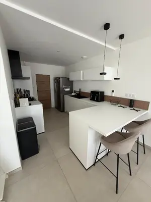 a white kitchen with a white table and chairs at New apartment, 3 bedrooms, sea view in Porto-Vecchio
