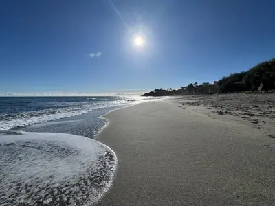a sandy beach with the sun in the sky at Appartement avec piscine en Bord de Mer - Corse in Linguizzetta