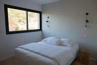 a white bedroom with a bed with a window at So Home in Porto-Vecchio
