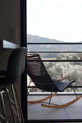 a rocking chair sitting in front of a window at So Home in Porto-Vecchio