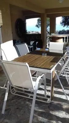 a wooden table with white chairs around it at Appartement Sole e Mare in Furiani