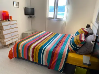 a bedroom with a bed with a colorful striped comforter at Superbe appartement type mini villa vue mer panoramique in Olmeto