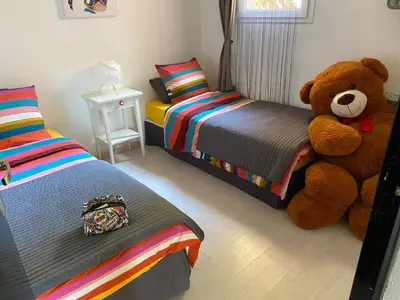 a bedroom with two beds and a large teddy bear at Superbe appartement type mini villa vue mer panoramique in Olmeto