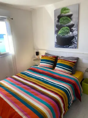 a bed with a colorful striped blanket in a bedroom at Superbe appartement type mini villa vue mer panoramique in Olmeto