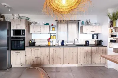 a kitchen with wooden cabinets and a stainless steel refrigerator at La Vista - Climatisé vue mer in Grosseto-Prugna