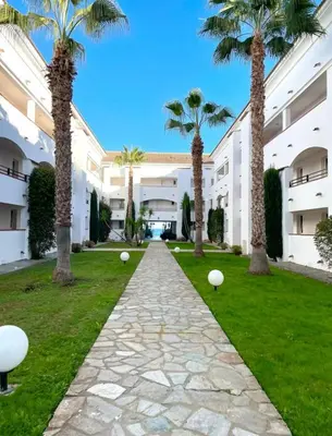 a walkway in front of a building with palm trees at Appartement en bord de mer in San-Nicolao