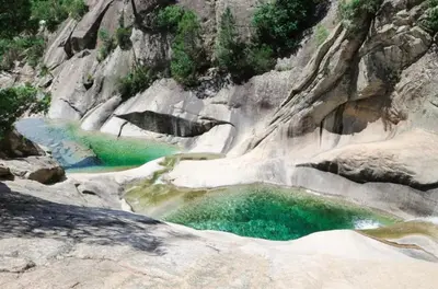 a pool of emerald green water in a rocky canyon at Appartement en bord de mer in San-Nicolao