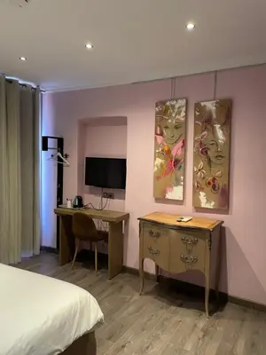a hotel room with a bed and a desk and a television at Chambre Le Chevalblanc