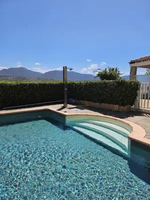 a swimming pool with blue water and mountains in the background at Mini-villa avec vue mer et piscine in Olmeto