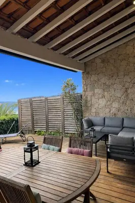 a patio with a wooden deck with a table and chairs at Mini-villa avec vue mer et piscine in Olmeto