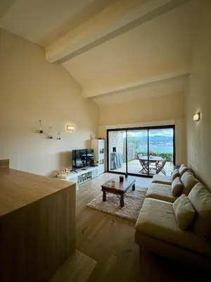 a living room with a couch and a large window at Mini-villa avec vue mer et piscine in Olmeto