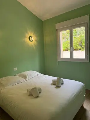 a bedroom with a white bed with a window at Mini-villa avec vue mer et piscine in Olmeto