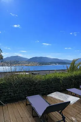 a couple of chairs sitting on a patio overlooking a lake at Mini-villa avec vue mer et piscine in Olmeto