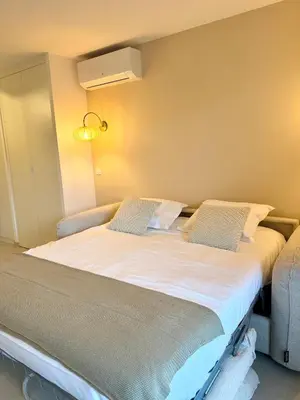 a bedroom with a large bed with white sheets at Studio neuf avec terrasse centre de Propriano in Propriano
