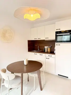 a kitchen with a wooden table and white cabinets at Studio neuf avec terrasse centre de Propriano in Propriano