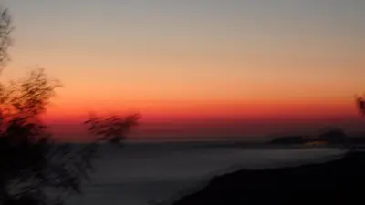 a sunset over the ocean with trees in the foreground at Villa Confina in Villanova