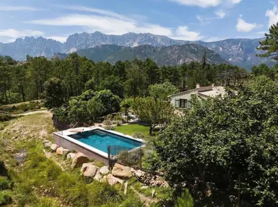 a house with a swimming pool in a field with mountains at U Ponte Grossu - Piscine Privée in Sari Solenzara
