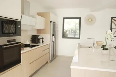 a kitchen with white counters and a black appliance at villa la baies des anges in Calcatoggio