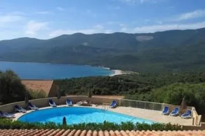 a swimming pool with chairs and a view of a lake at Magnifique duplex vue mer avec clim wifi piscine mer à pied in Serra-di-Ferro