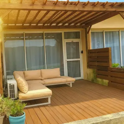 a patio with a couch on a wooden deck at Magnifique duplex vue mer avec clim wifi piscine mer à pied in Serra-di-Ferro