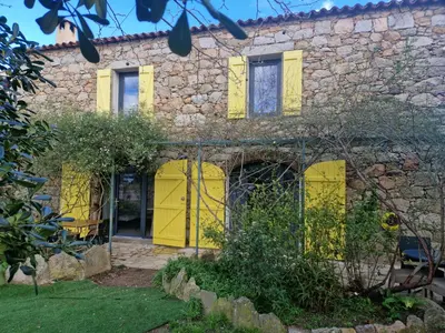a stone house with yellow doors and windows at Le vieux moulin in Porto-Vecchio