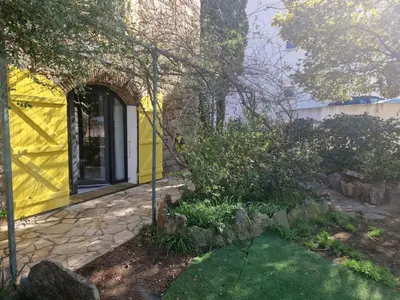 a yellow house with a yellow door and a yard at Le vieux moulin in Porto-Vecchio