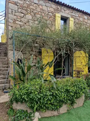 a stone building with yellow doors and plants in front at Le vieux moulin in Porto-Vecchio