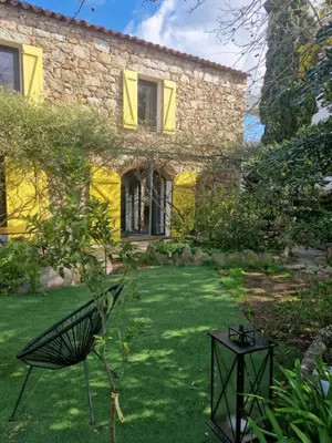 a garden with a chair and a building at Le vieux moulin in Porto-Vecchio