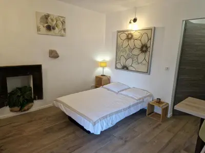 a white bedroom with a bed and a fireplace at Le vieux moulin in Porto-Vecchio