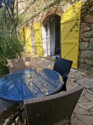 a patio table with chairs and a yellow door at Le vieux moulin in Porto-Vecchio