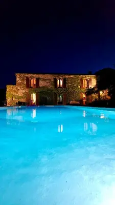 a large pool of blue water in front of a building at Chambres de charmes - 3 chambres indépendantes avec salles de bains privatives in Corte
