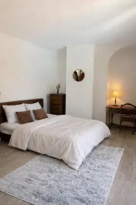 a bedroom with a large white bed with a rug at Chambres de charmes - 3 chambres indépendantes avec salles de bains privatives in Corte