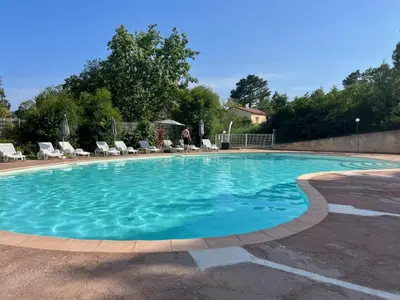 a large pool with blue water in a yard at Mini-villa Lisa 30 Résidence avec piscine Accès plage à pied in Sari Solenzara
