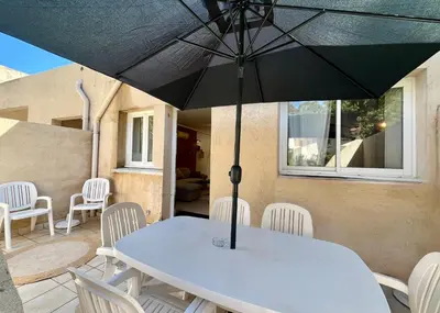 a table and chairs with an umbrella on a patio at Mini-villa Lisa 30 Résidence avec piscine Accès plage à pied in Sari Solenzara