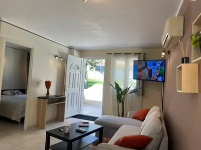 a living room with a couch and a tv at Mini-villa Lisa 30 Résidence avec piscine Accès plage à pied in Sari Solenzara