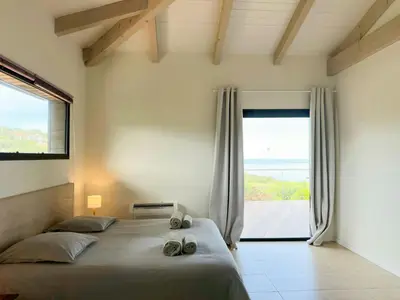 a bedroom with a bed and a large window at Villa On One Hectare Facing The Gulf Of Ajaccio in Coti-Chiavari