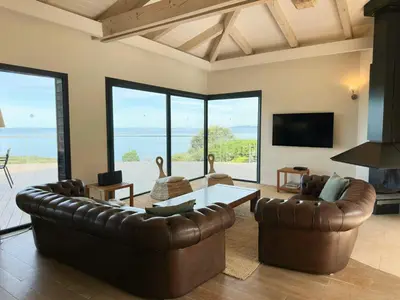 a living room with a leather couch and a table at Villa On One Hectare Facing The Gulf Of Ajaccio in Coti-Chiavari