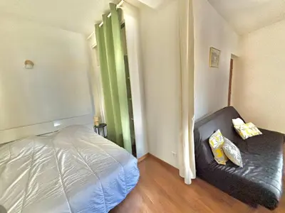 a bedroom with a bed and a black leather couch at Studio centre-ville rue fesch Ajaccio in Ajaccio