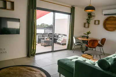 a living room with a couch and a table at Résidence Porticcio Vacations Vue Mer Piscine & Jacuzzi in Grosseto-Prugna