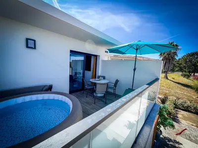 a bedroom with a bed with a green headboard and a window at Résidence Porticcio Vacations Vue Mer Piscine & Jacuzzi in Grosseto-Prugna