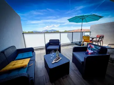 a balcony with two couches and a table and an umbrella at Résidence Porticcio Vacations Vue Mer Piscine & Jacuzzi in Grosseto-Prugna