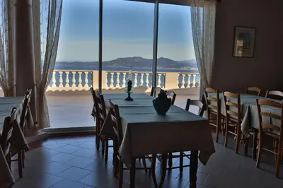 a dining room with tables and chairs and a large window at le Belvedere in Coti-Chiavari