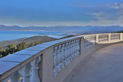 a balcony with a view of the water and mountains at le Belvedere in Coti-Chiavari