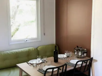 a table with wine glasses and a green couch at Mobil-home confortable avec terrasse pour 4 personnes à Vico - API-1-52-838 in Vico