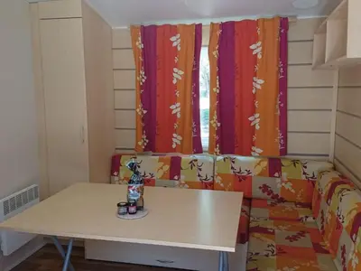 a room with a table and a couch with curtains at Mobil home 6 personnes avec terrasse à Vico - API-1-52-841 in Vico
