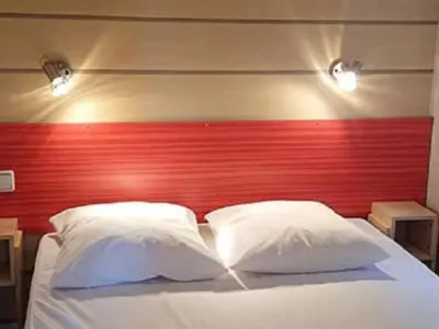a bed with a red headboard and two white pillows at Mobil home 6 personnes avec terrasse à Vico - API-1-52-841 in Vico